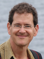 Woman with blond hair and pastel dress sitting on a rock wall outdoors